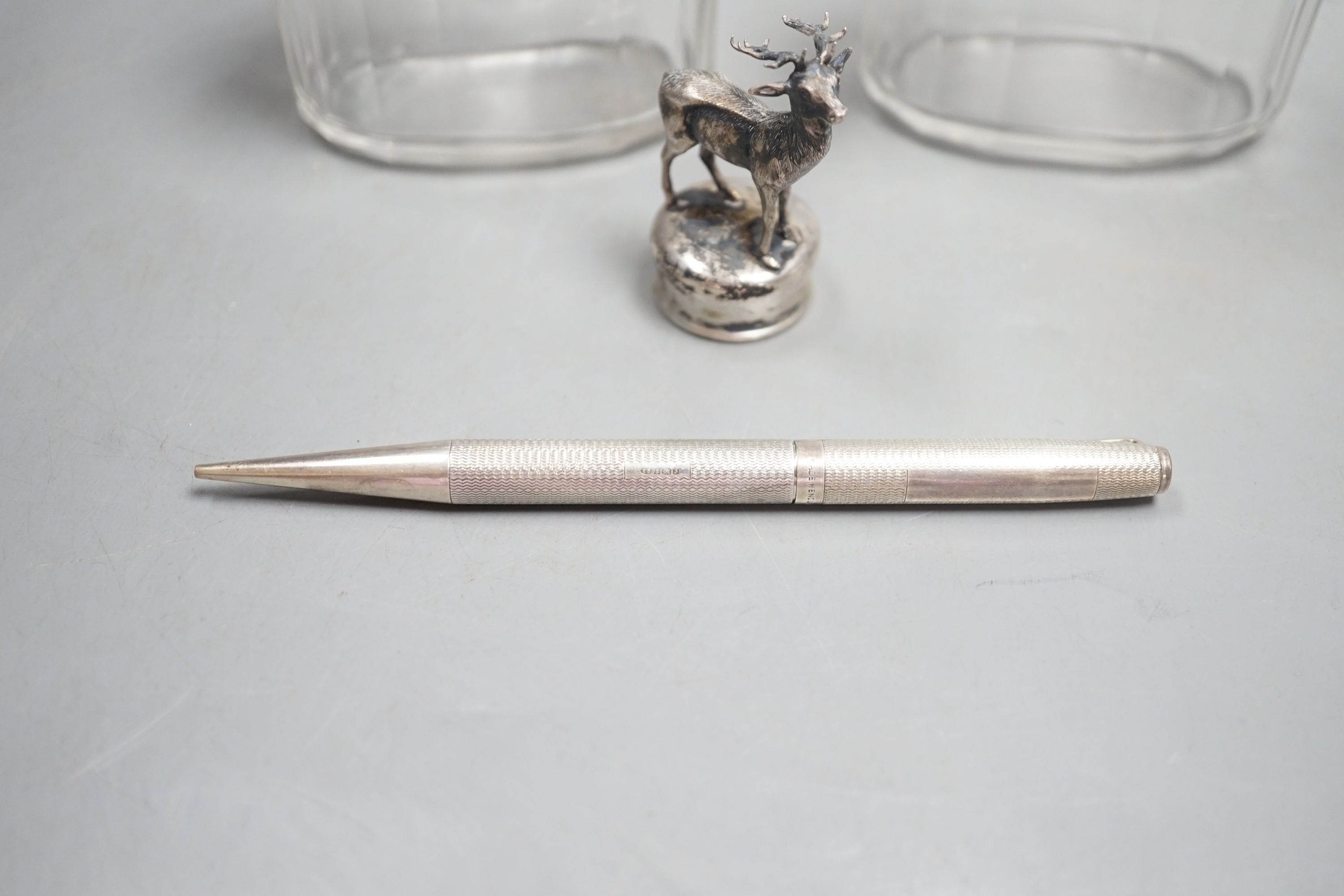 A white metal stag mounted bottle top,48mm, a pair of Edwardian silver topped glass toilet jars and a silver propelling pencil.